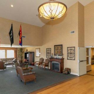 A spacious living room featuring a high ceiling, elegant chandelier, and comfortable seating around a fireplace.