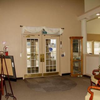 A lobby interior featuring glass doors, seating area, and display cabinet.