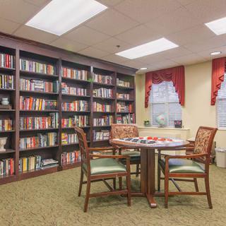 A cozy library reading area with bookshelves, a table, and chairs.