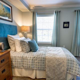 A cozy and well-decorated bedroom with a neatly made bed, decorative pillows, and soft lighting.