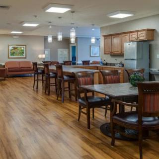 A cozy dining area with multiple tables and chairs, featuring a kitchen space in the background.