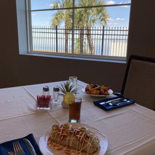 A beautifully set table with desserts and pastries, overlooking a palm tree through the window.