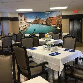A dining room with elegant table settings and a large wall mural depicting a scenic view.