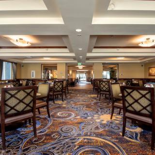 An elegantly furnished dining room with patterned carpet and neatly arranged empty chairs.
