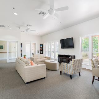 A well-lit living room with comfortable seating and a wall-mounted TV.