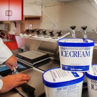 A chef scoops ice cream from tubs in a modern kitchen setting.