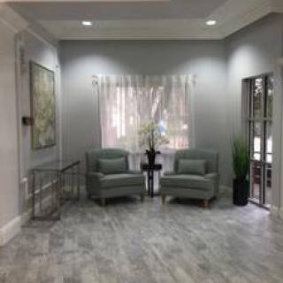 A modern living room with two chairs, artwork on the wall, and decorative plants.