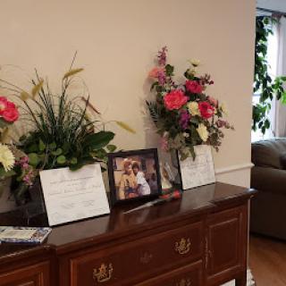 A beautifully arranged display featuring vibrant flowers and a cherished photograph on a wooden dresser.