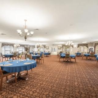 Spacious dining room with blue tablecloths and elegant chandeliers.