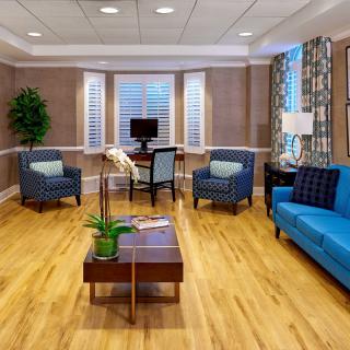 A modern living room with wooden flooring, stylish furniture, and large windows.
