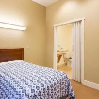 A cozy bedroom with a neatly made bed and an open door leading to an adjoining room.