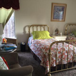 A cozy bedroom with twin beds and floral bedding, featuring vintage-style decor.