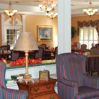 A cozy lounge area with traditional decor featuring armchairs, a table lamp, and chandeliers.