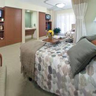 A cozy and well-furnished hospital room with a comfortable bed.