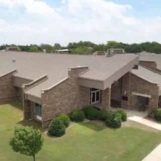 Aerial view of a modern residential building surrounded by greenery and clear skies.
