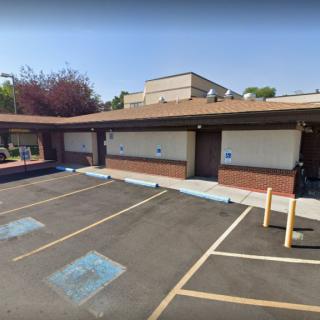 An empty parking lot in front of a building with handicap spaces and trees in the background.