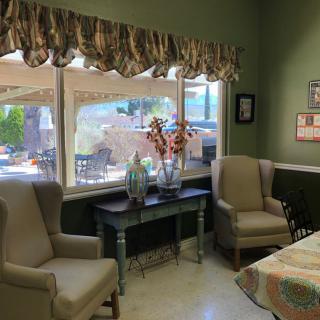 A cozy living room with two armchairs, a decorative table, and large windows overlooking an outdoor space.
