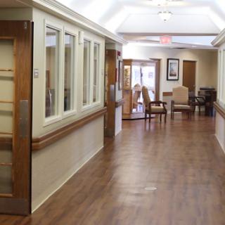 A serene hallway in a healthcare facility, featuring wooden floors and comfortable seating.