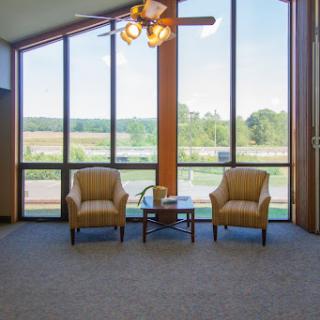 A bright and airy living space featuring two comfortable chairs and large windows offering a scenic view.