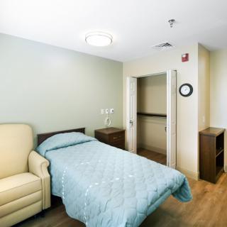 A minimalist hospital room with a single bed and chair.