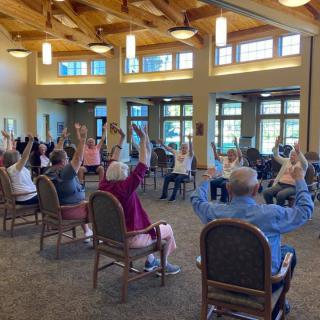 A group of seniors participating in a seated exercise class at a community center.