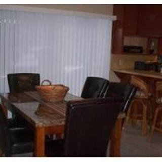 A cozy dining area with a wooden table, leather chairs, and kitchen bar stools.