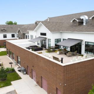 A modern residential building with a brick facade and rooftop outdoor seating area.