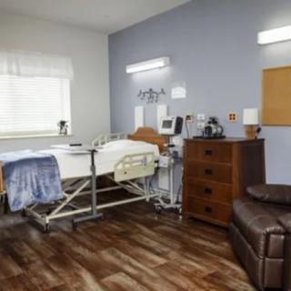 A modern hospital room featuring a bed, medical equipment, and comfortable furniture.