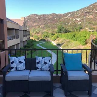 A scenic view from a balcony with comfortable seating and mountain landscape.