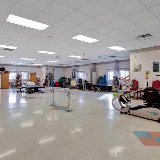 A spacious physical therapy room equipped with various exercise machines and rehabilitation tools.