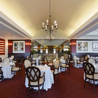 An elegant restaurant interior with tables and chairs arranged under a chandelier.