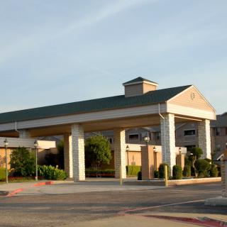 A building with a covered entrance and a surrounding parking area during the day.
