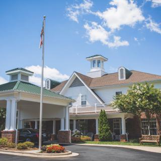 A building with a covered entrance and cupolas against a partly cloudy sky.