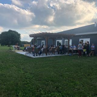 A lively outdoor gathering near a building, with people enjoying the day on a grassy lawn.