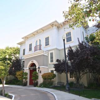 A residential building with a unique architectural design surrounded by trees and a street.