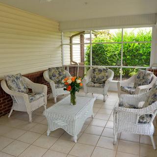 A cozy patio with wicker furniture arranged around a table adorned with flowers.