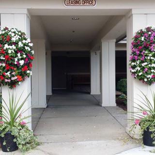 A building entrance adorned with colorful floral wreaths and potted plants.