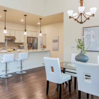 A modern open-plan dining and kitchen area featuring white furniture and elegant lighting.