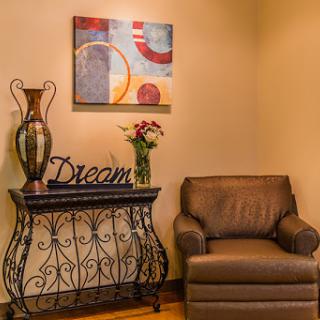 A cozy corner of a living room featuring elegant decor, a comfortable chair, and artistic elements.