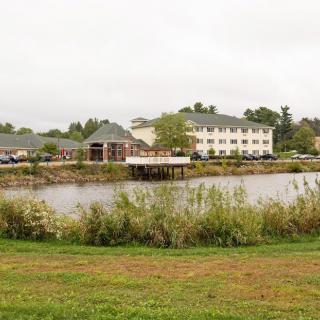 A serene view of a hotel near a pond surrounded by greenery.