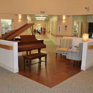 A cozy seating area in a hallway featuring a grand piano and comfortable chairs.