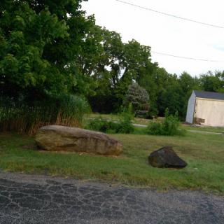 A serene outdoor scene featuring rocks and greenery, with a building in the background.