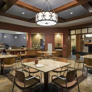 A modern restaurant dining area with tables, chairs, and a chandelier.