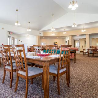 A spacious dining area with wooden tables and chairs, well-lit by ceiling lights.