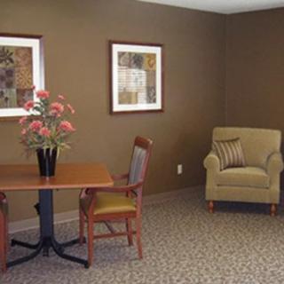A neatly arranged office space with a small table, chairs, and decorative artwork on the wall.