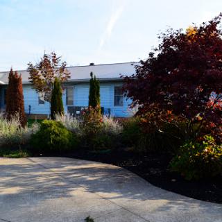 A serene view of a house with a well-maintained garden and driveway.