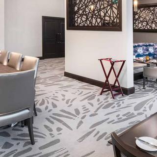 A modern dining area with patterned carpet and stylish seating, featuring decorative partition walls.