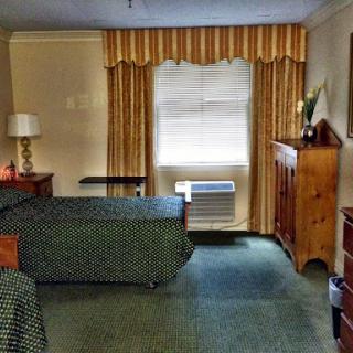 A cozy hotel room featuring a bed, window with curtains, and wooden furniture.