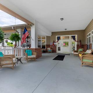 A welcoming porch area with comfortable seating and plants, featuring an American flag.