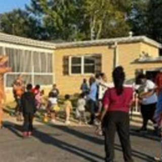 A community gathering outside with children and adults, some dressed in costumes.